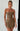 Woman wearing a strapless brown dress against a white wall.